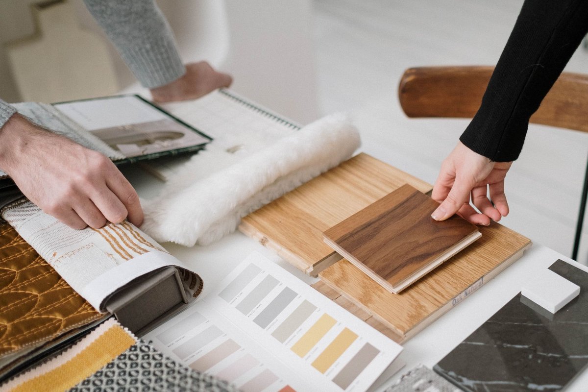 Two professionals reviewing stone, metal, and glass material samples on a white table