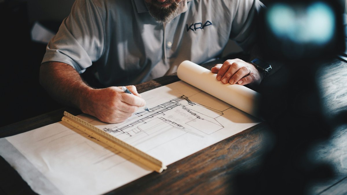 Architects reviewing blueprints around a drafting table in a bright, minimalist studio