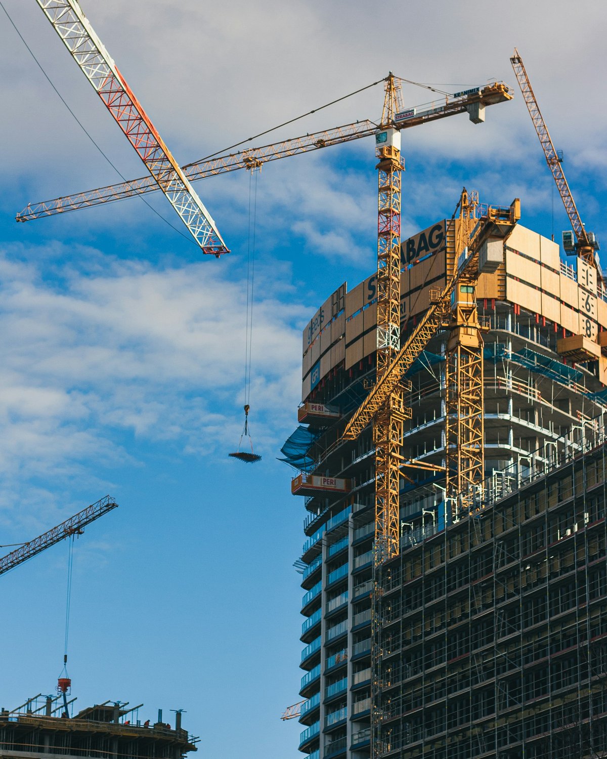 Brutalist-style skyscraper under construction, exposed steel and concrete against a clear sky